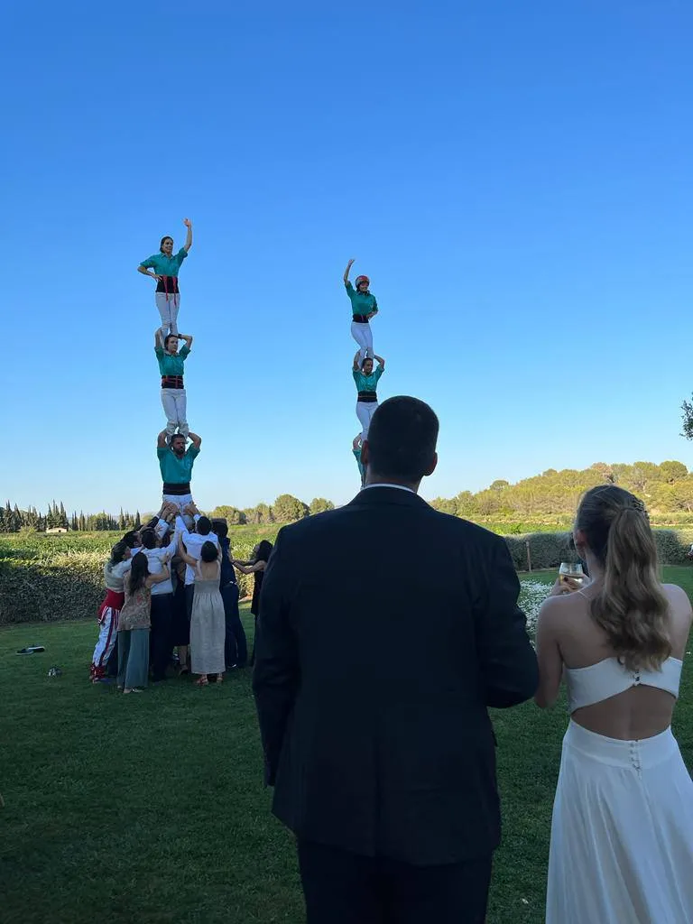 Els nuvis mirant dos pilars castellers simultanis en un jardí durant el seu casament